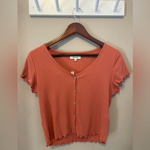 Ribbed top with delicate ruffled sleeves and hem. Buttoned front, crop length.